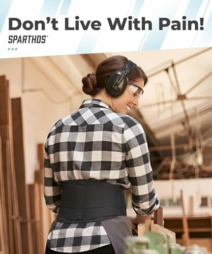 Person wearing back brace while woodworking, with safety gear.